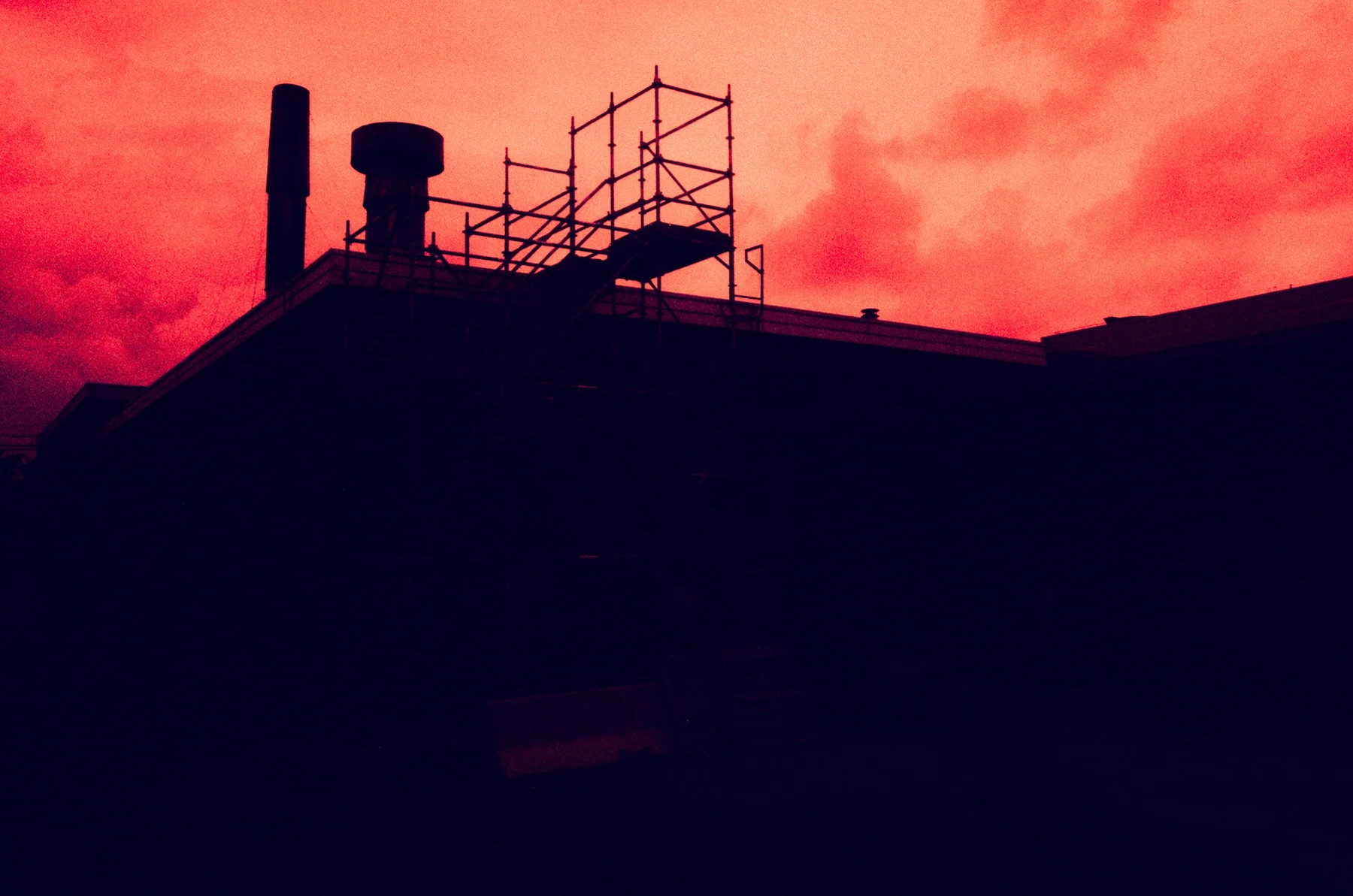 Rooftops silhouetted against a red-orange sky