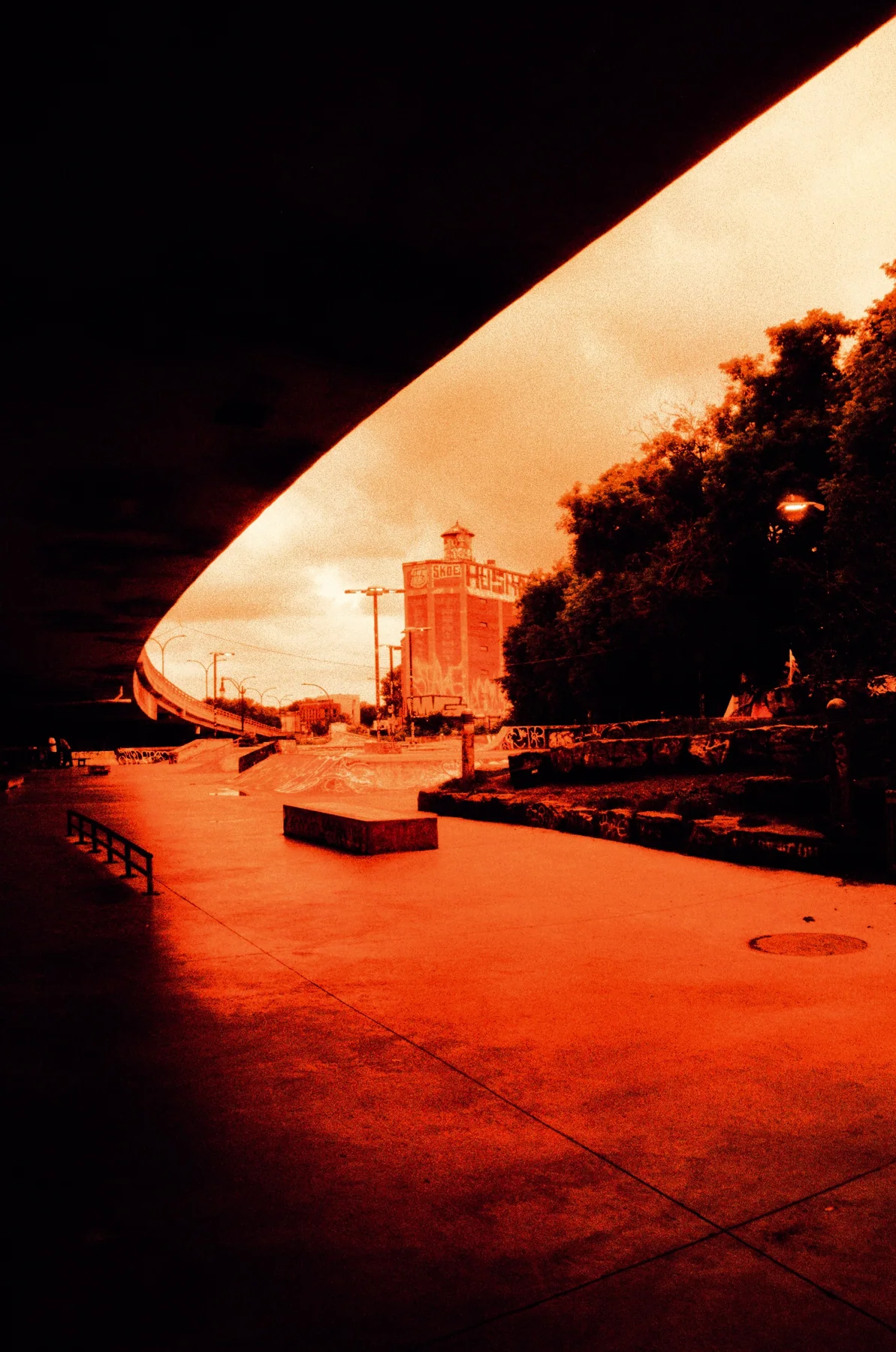 Warm sunlight beyond the dark curve of an overpass