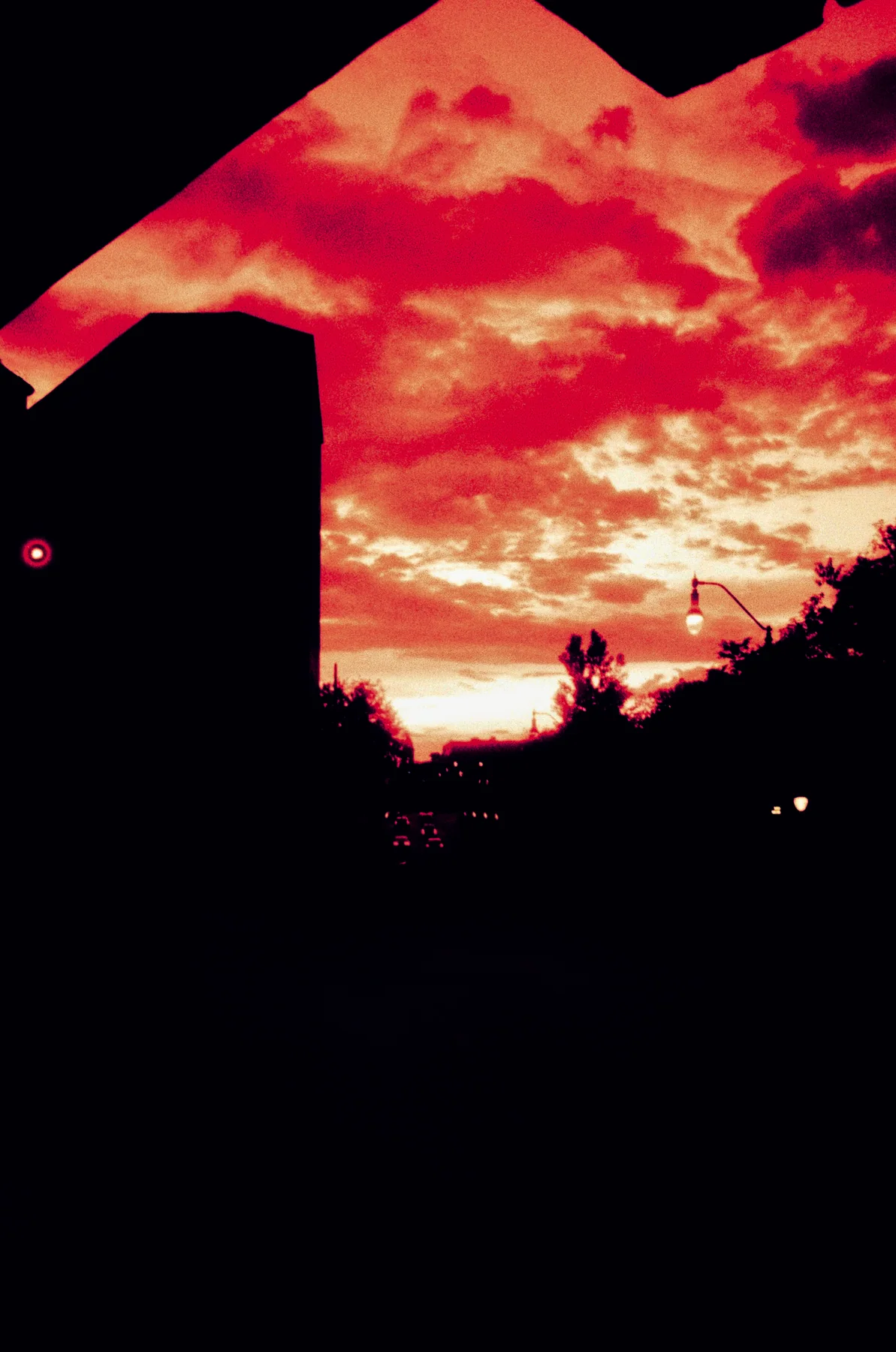 A building silhouetted against vivid red clouds