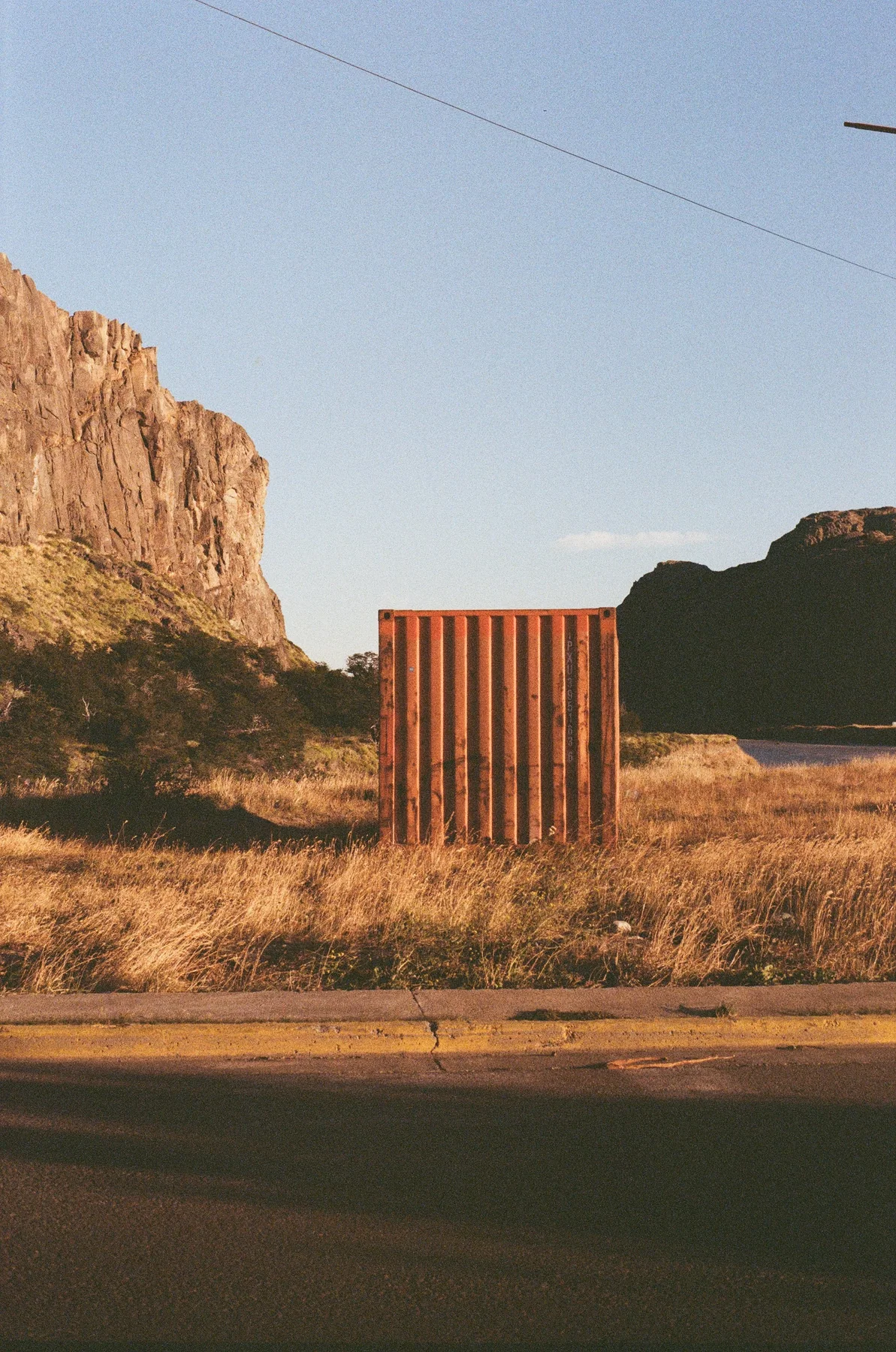 An open road passing sunlit rock formations