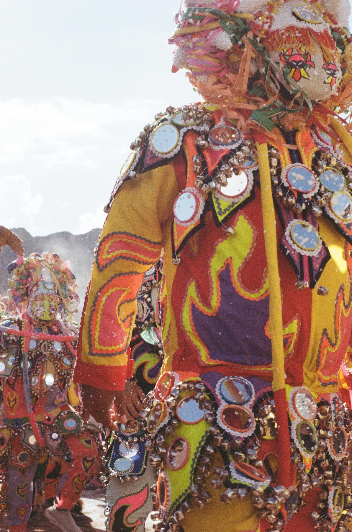 A performer wearing a colourful mask and embroidered costume