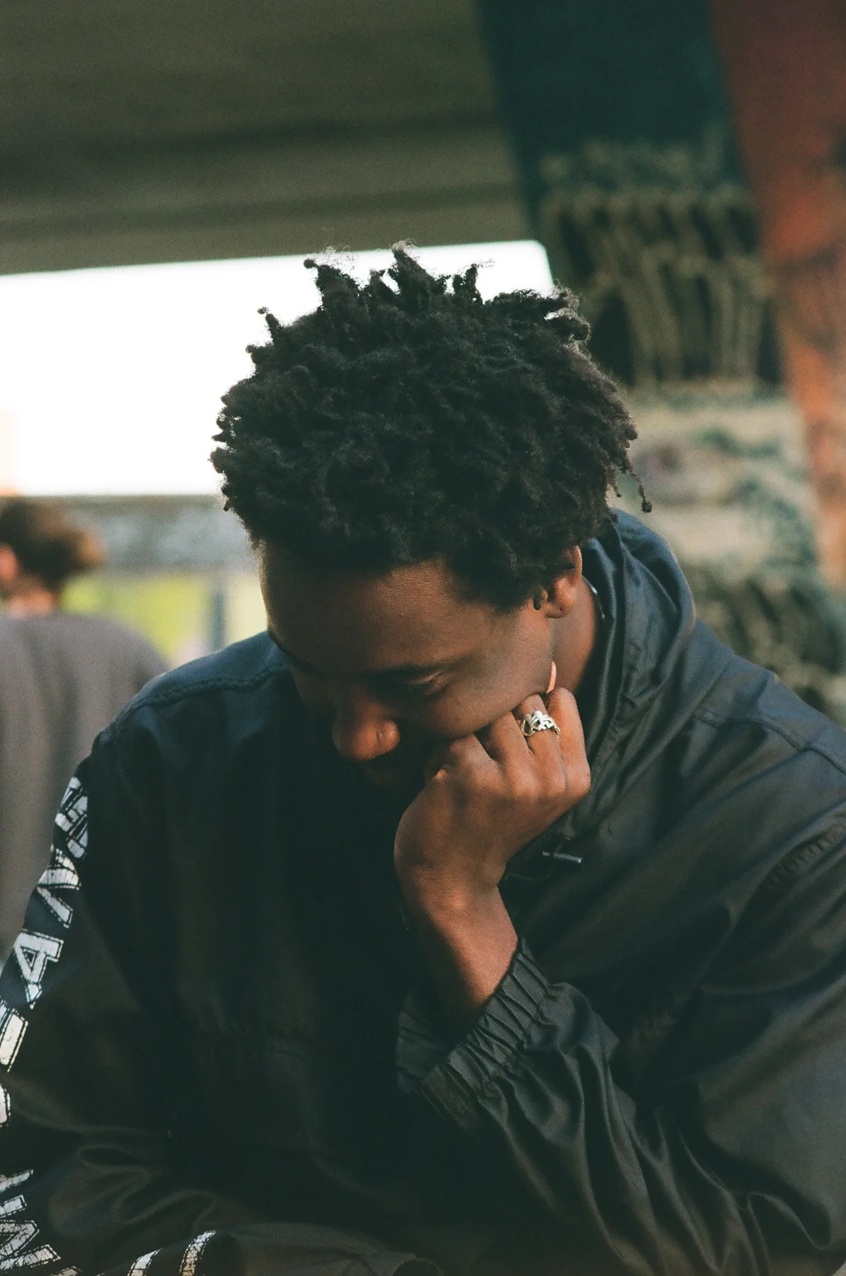 A seated person resting their head against their hand