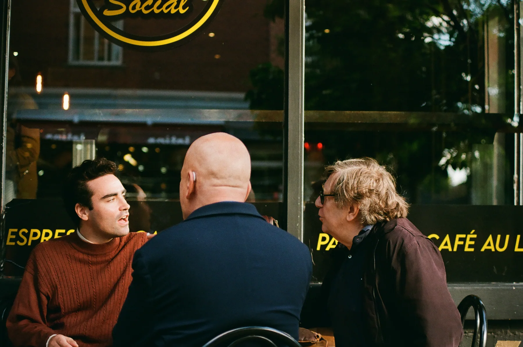 Three people in conversation outside a café