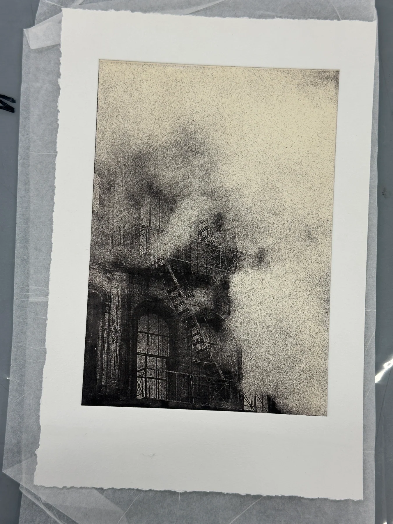 A photogravure of a building emerging through steam, surrounded by the edges of the paper