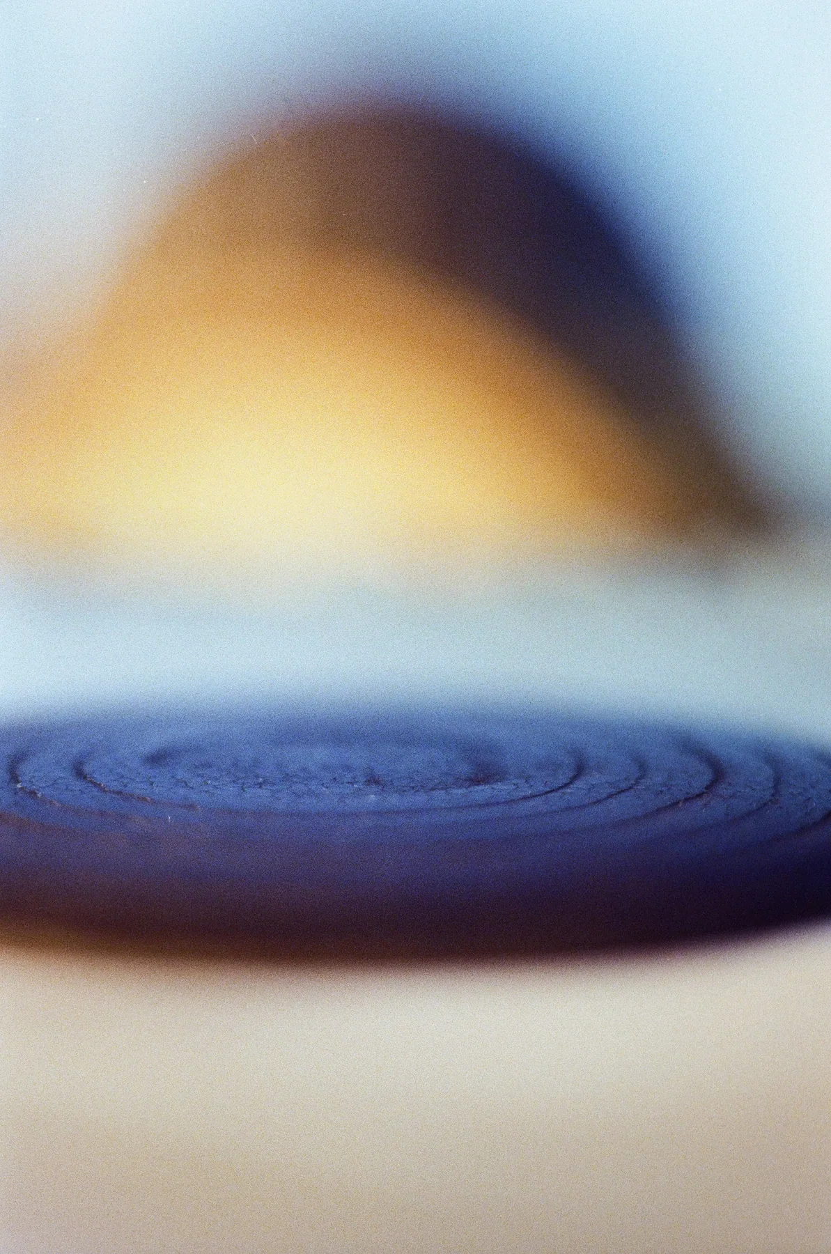 A blue circular form surrounded by warm, blurred light