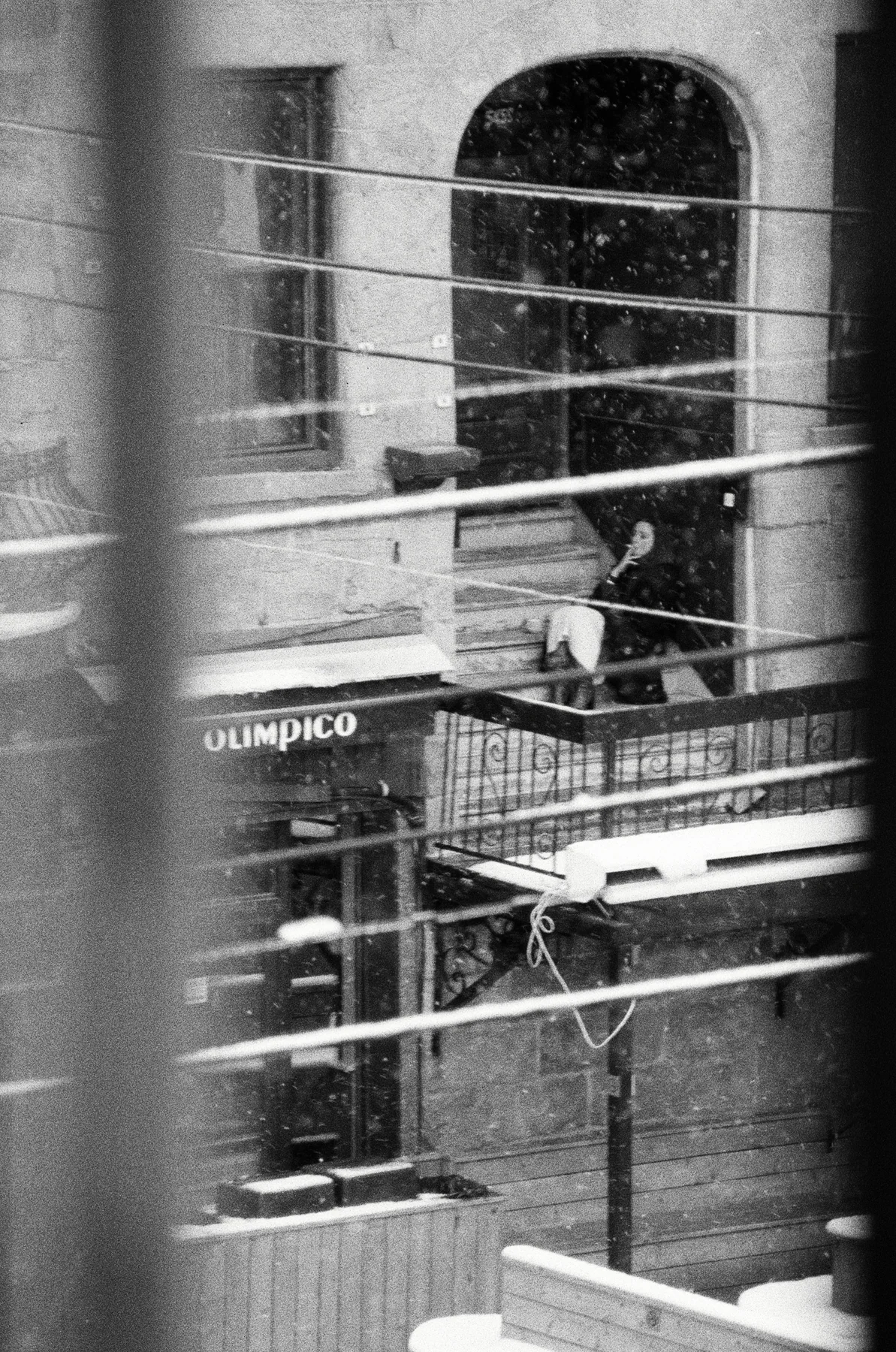 A distant figure framed by balconies and railings