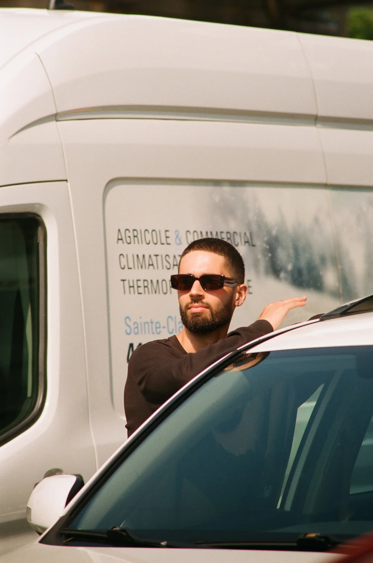 A man in sunglasses leaning against a vehicle