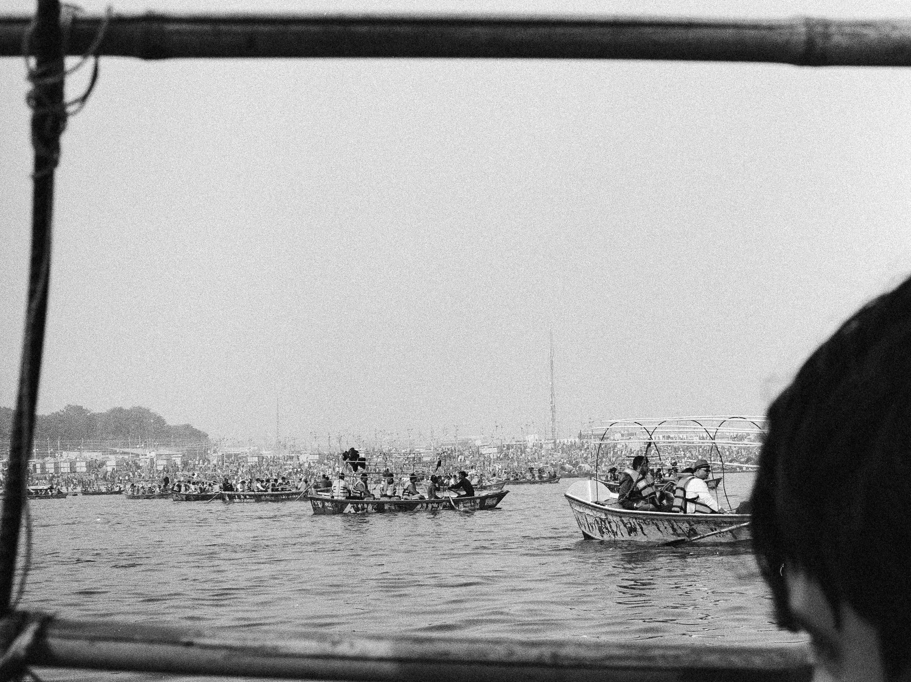 People gathered along a shoreline seen past a foreground figure