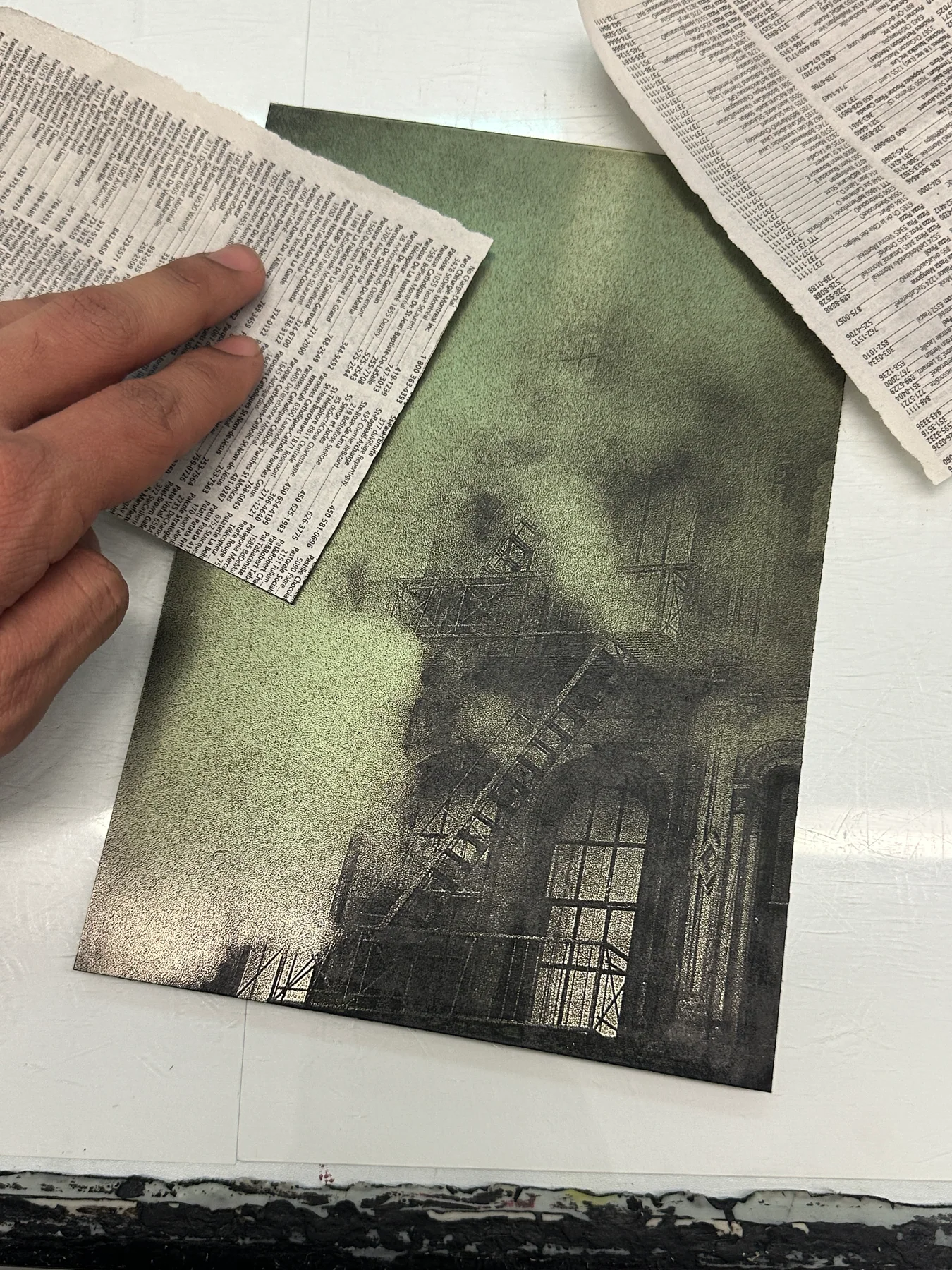 A hand beside a building photogravure and sheets of newspaper
