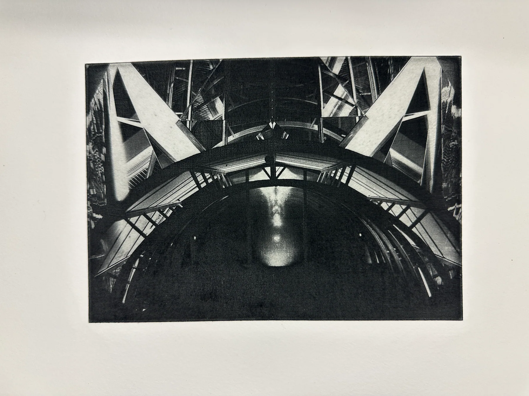 A dark photogravure of a bridge and its reflection