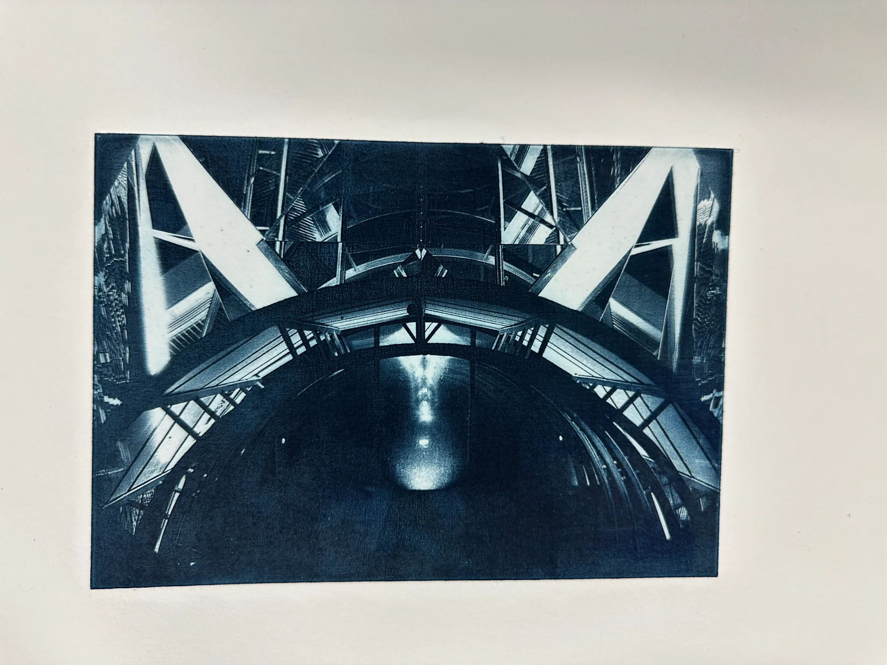 A blue photogravure of a bridge and its reflection